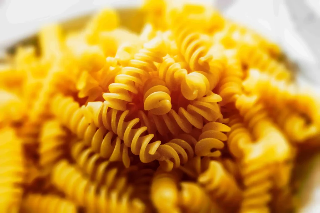 Nahaufnahme von gekochten Fusilli-Nudeln mit einem weichgezeichneten Hintergrund, der die Spiralform und die gelbe Farbe der Nudeln hervorhebt, aufgenommen im Stil der Food-Fotografie Hannover.