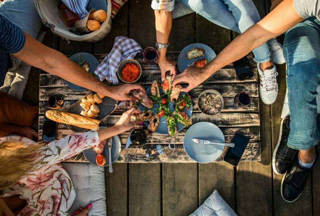 Close up of hands taking food at picnic.